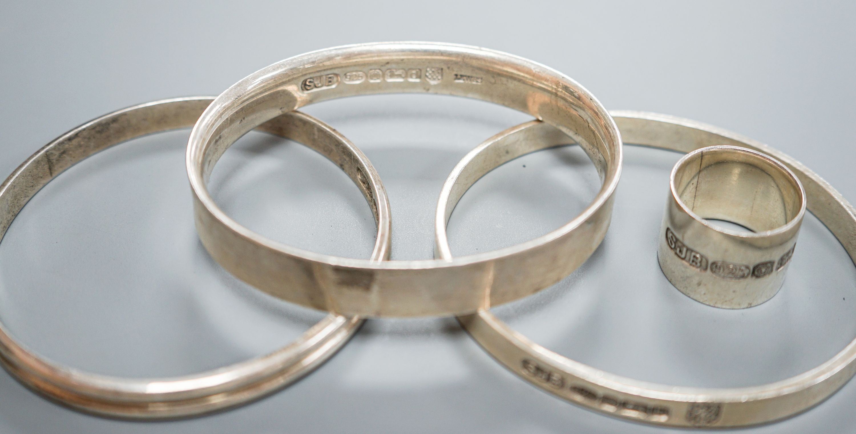 Three modern silver bangles and a large silver band, all by Simon J. Beer of Lewes